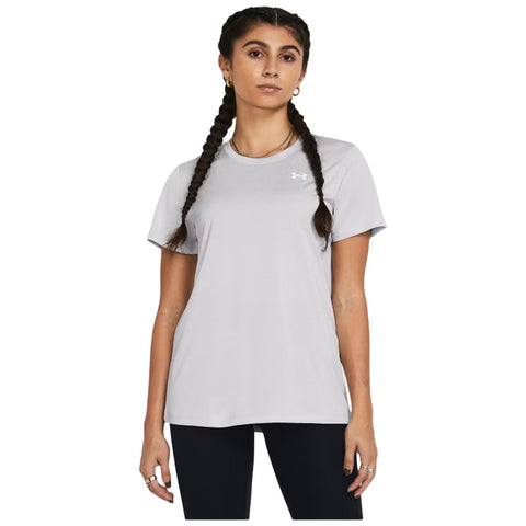 A young woman stands wearing a light gray t-shirt and black leggings with two long braids. She faces forward with a neutral expression against a plain background.
