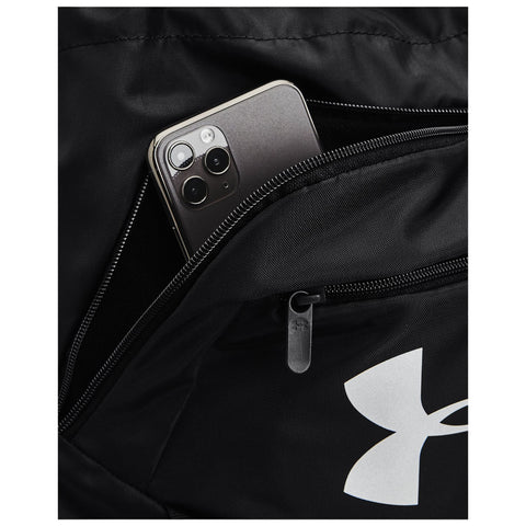 A black backpack features a partially unzipped pocket containing a smartphone with a three-camera arrangement visible on its back while the backpack's logo is also prominently displayed.