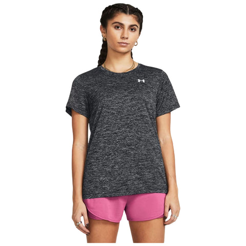 A person is standing, wearing a dark gray t-shirt and pink shorts, with braided hair. The background is plain white, emphasizing the clothing and the individual.