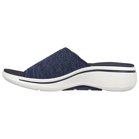 A navy blue slip-on shoe features a textured upper and a thick white sole showcasing a slight curve while positioned against a plain background highlighting its design.