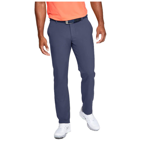 A person stands, showcasing navy pants and white shoes while wearing an orange shirt. The back view emphasizes the fit and style of the pants in a casual setting.