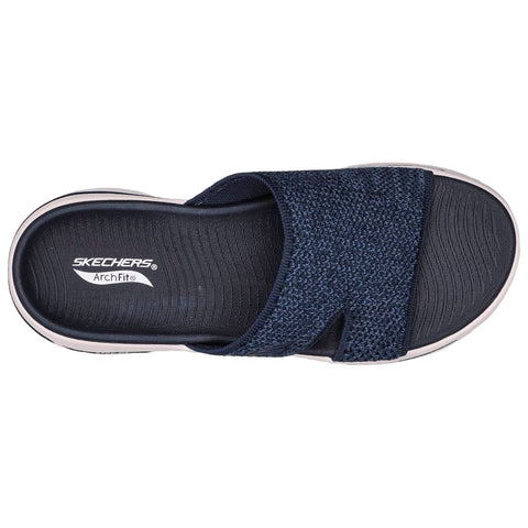 Shoe is a navy blue slide sandal with a textured fabric upper and a cushioned black insole featuring Skechers ArchFit logo on it, designed for comfort and casual wear.
