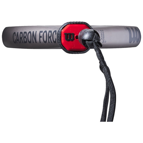 A tennis racket featuring a gray frame with the text "CARBON FORGE" and a red and black handle is positioned horizontally with a black strap attached for grip.