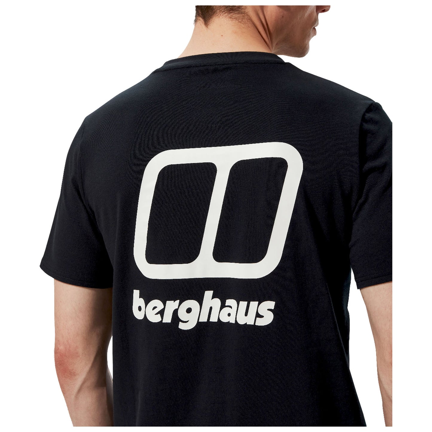 A person is wearing a black t-shirt featuring a large white logo design on the back with the text "berghaus" underneath the logo in bold letters