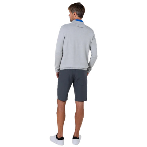 A man stands with his back turned wearing a grey sweater and dark shorts in a neutral backdrop, suggesting a casual, relaxed environment appropriate for outdoor activities.
