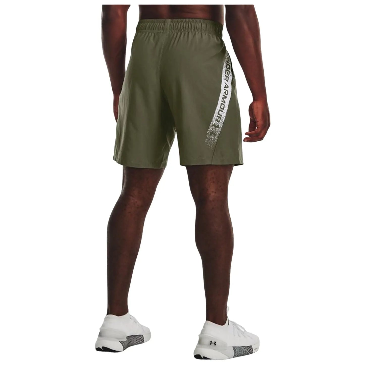 A person wearing khaki athletic shorts and white sneakers stands facing away the shorts feature a logo on the side in a sporty context.