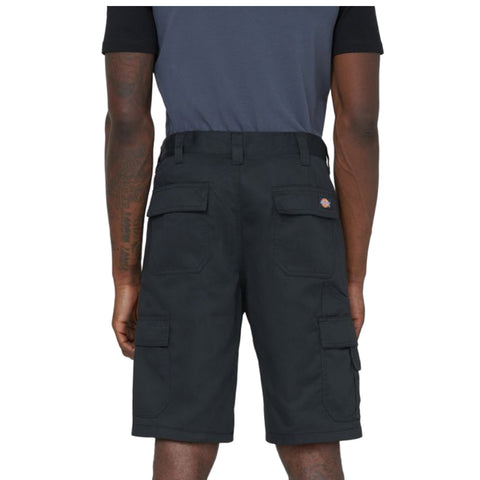 Black cargo shorts are worn by an individual standing with their back to the viewer showcasing multiple pockets and a logo on the waistband in a neutral setting.