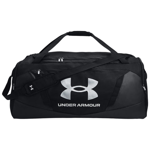 A black duffel bag displays a large silver Under Armour logo and carries a shoulder strap alongside two handles in a plain background.
