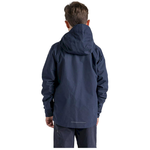 A person wearing a dark navy jacket faces away with a hood up in a neutral space, suggesting a casual outdoor setting. The jacket appears functional and weather-resistant.