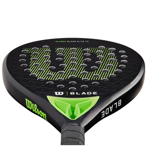 A black paddle with a circular face featuring a green and white hexagonal design and the text "WILSON BLADE ELITE TX" is positioned vertically against a neutral background.