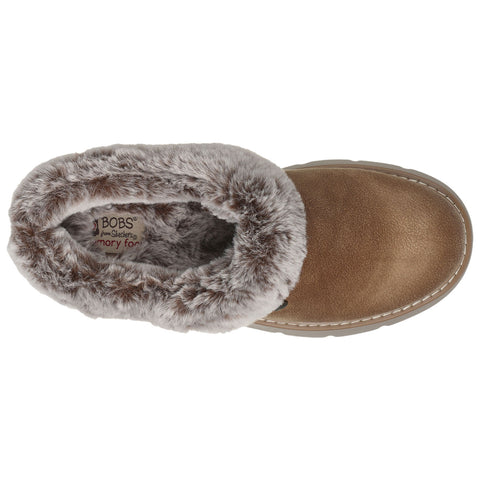 A brown slipper with a soft, fur-lined collar sits on a flat surface showcasing its cozy design and texture labeled BOBS from Skechers memory foam inside.