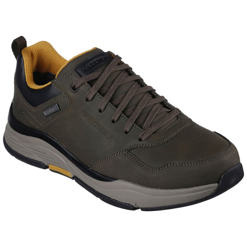 A green athletic shoe is displayed with a lace-up design featuring a black and yellow interior and a thick sole suitable for outdoor activities in a neutral background.