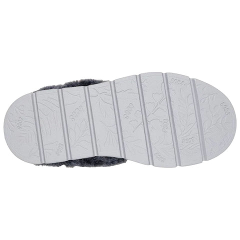A gray slipper's sole rests flat displaying textured patterns for grip while being surrounded by a soft fur upper indicating comfort and casual indoor use.