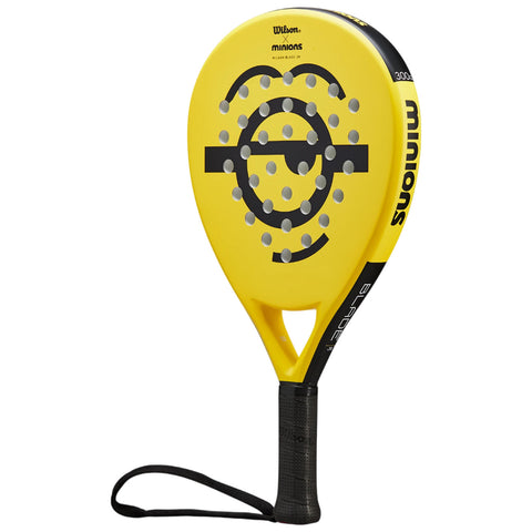 A bright yellow paddle racket features a large circular design with black markings and raised dots for grip. It has a textured black handle and a wrist strap for secure handling.