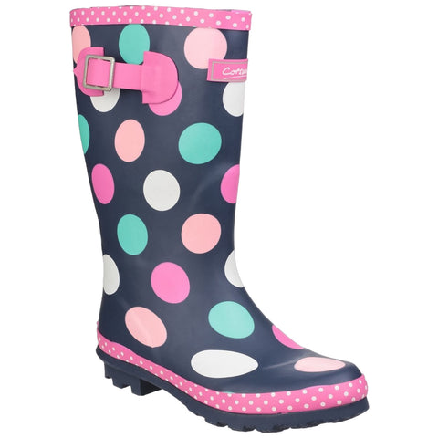 A polka-dotted rain boot stands upright displaying a dark background with colorful circles and a pink polka-dotted trim at the top and sole designed for wet conditions