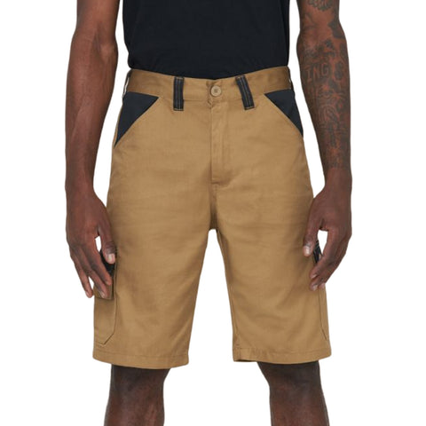 Tan shorts are worn by a person standing upright with hands at their sides The shorts feature black accents near the pockets and are part of a casual outfit in a neutral setting