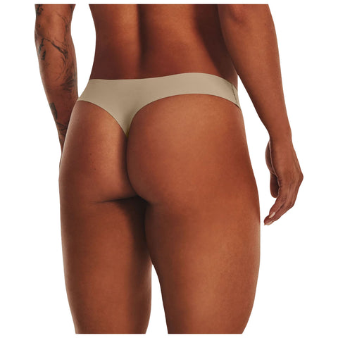 A person's lower back and thighs are prominently displayed while wearing a simple beige thong. The individual is turned slightly, showcasing a muscular physique against a plain background.