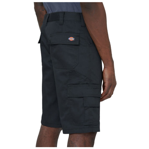 A person stands wearing black cargo shorts with multiple pockets the garment features a brand tag on the back indicating durability suitable for casual or work environments.