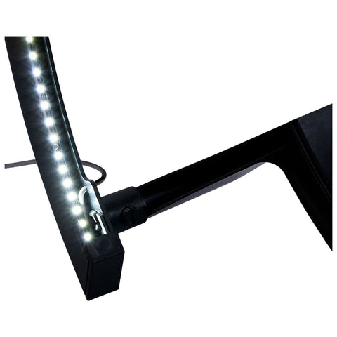 A black table lamp with an LED light strip attached to its curved arm illuminates a workspace providing ambient lighting in a home or office setting.