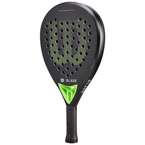 A black paddle with a perforated surface and green accents rests upright. The paddle is designed for sports, featuring a textured grip and a prominent brand logo across the head.