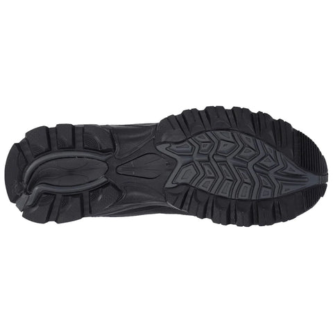 A black athletic shoe sole is displayed showing its tread pattern designed for traction and stability on various surfaces in an indoor or studio setting.