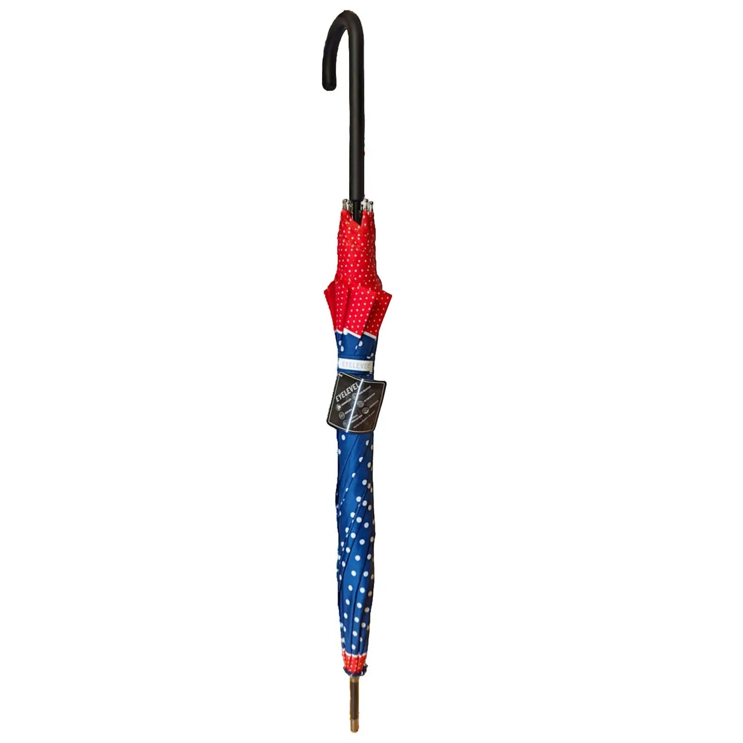 A colorful umbrella with a red top featuring white polka dots and a blue shaft adorned with white dots stands upright against a plain background, suggesting it is ready for use in rain or sun.