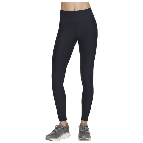 A pair of black leggings are displayed standing upright showcasing a ribbed texture with a high waistband alongside gray athletic shoes suggesting an active lifestyle.
