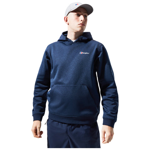 A young person wearing a navy hoodie and matching pants stands confidently with one hand on their hip and gazes slightly upward against a white background.