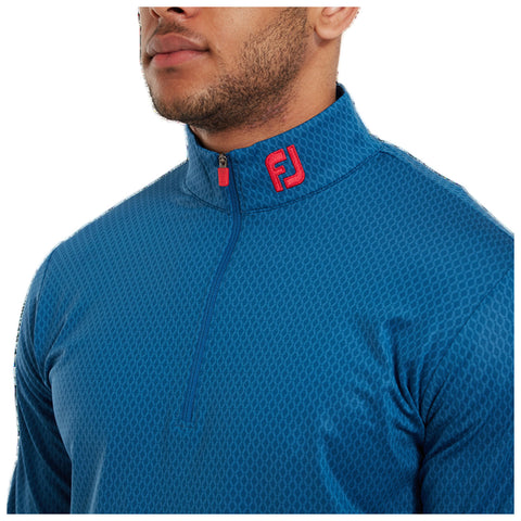 A blue zip-up shirt with a textured pattern is worn by a man featuring a red logo on the collar in a neutral indoor setting highlighting the garment's stylish design.