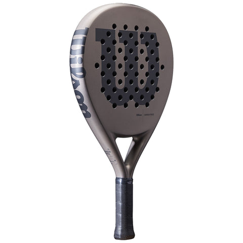 A paddle with a perforated surface prominently features a large dark logo and a textured handle designed for grip used in sporting activities like paddle tennis or pickleball.