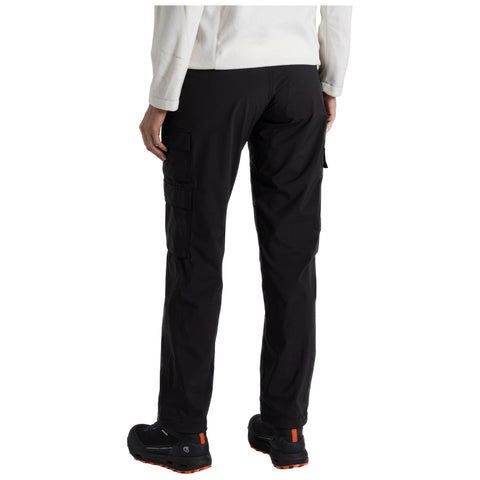 Black cargo pants are worn by a person standing with their back facing the viewer in a casual indoor setting. The person wears black shoes with orange accents and a light-colored top.