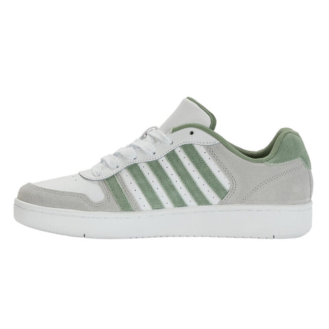 A sneaker with a white leather body features light green suede accents and three green stripes on the side resting horizontally against a plain white background.