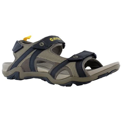 A brown and black sandal features adjustable straps and a textured rubber sole designed for outdoor activities with a yellow tag on the heel indicating brand identity.