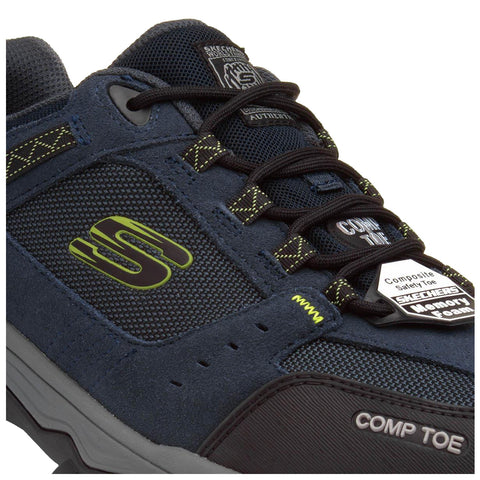 A dark blue sneaker with a composite safety toe and a mesh upper is shown resting on a flat surface featuring the brand logo and "COMP TOE" label on the side.