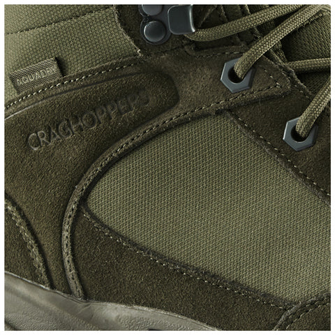 A green hiking boot features textured suede and fabric materials with a reinforced toe and secure lacing system showing brand name Craghoppers and tag labeled Aquadry