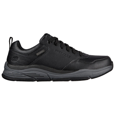 A black sneaker with a sturdy design features a textured upper and a thick gray sole positioned on a white background, showcasing its modern athletic style.