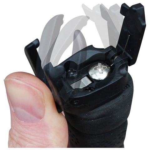 A hand holds a black device with an open lid revealing a silver battery compartment while the lid appears to be tilted upward in a hinge motion indicating battery replacement or maintenance.