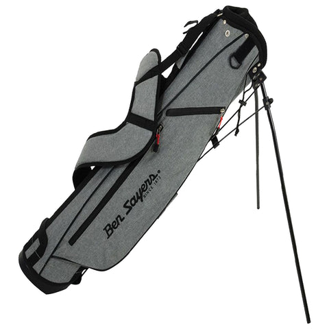 A golf bag is upright with a stand extended showcasing its gray fabric design and black accents featuring the brand name prominently displayed. It is positioned for easy access to golf clubs.