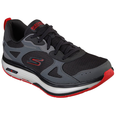 A black and gray athletic shoe with red accents rests against a white background featuring a mesh upper and cushioned sole designed for comfort and support during workouts.