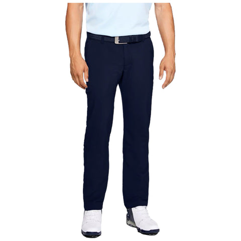 A pair of navy pants is being worn by a person standing upright who has their left hand resting slightly at their side while they are dressed in a light blue shirt and white shoes.