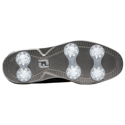 A black golf shoe sole features six clear plastic spikes arranged in two rows for traction on grass surfaces with textured patterns for grip and support during play.