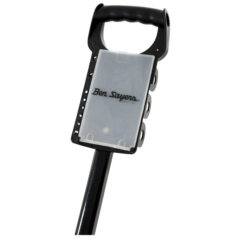 A metal detector is positioned upright with a black handle and a detection head featuring buttons and a transparent casing. It is designed for locating metals underground in various outdoor environments.