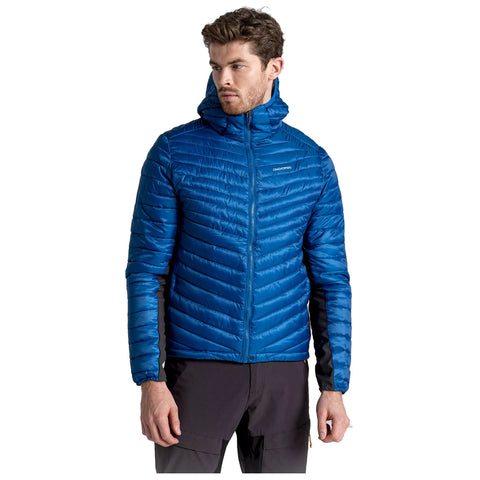 A man is wearing a bright blue puffy jacket with a hood standing upright and looking slightly to the side in a neutral setting with no visible background elements.