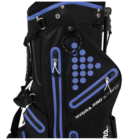 A black and blue golf bag stands upright featuring multiple zippered compartments and a reinforced top handle designed to carry golf clubs and accessories in a golfing setting.