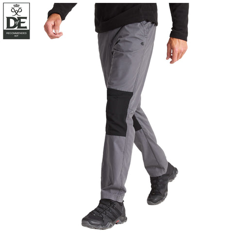A person wearing gray and black outdoor pants is walking. The environment is neutral with no visible background details. The pants feature distinct panels for added durability.