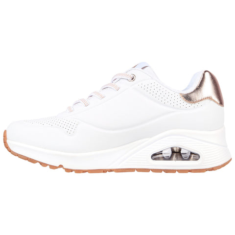 A white athletic shoe with a sleek design features a metallic accent at the heel and a visible air cushion in the sole, presented on a plain background.