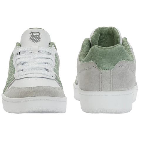 A green and white sneaker lies flat showcasing its top and sole. The shoe features laces and textured patterns on the sole with a logo visible inside the shoe.