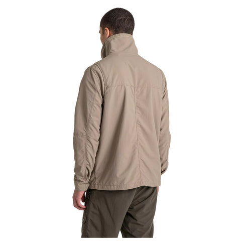 A person wears a light beige jacket with a high collar standing with their back facing the viewer in a neutral background. The surrounding environment appears minimalistic and uncluttered.