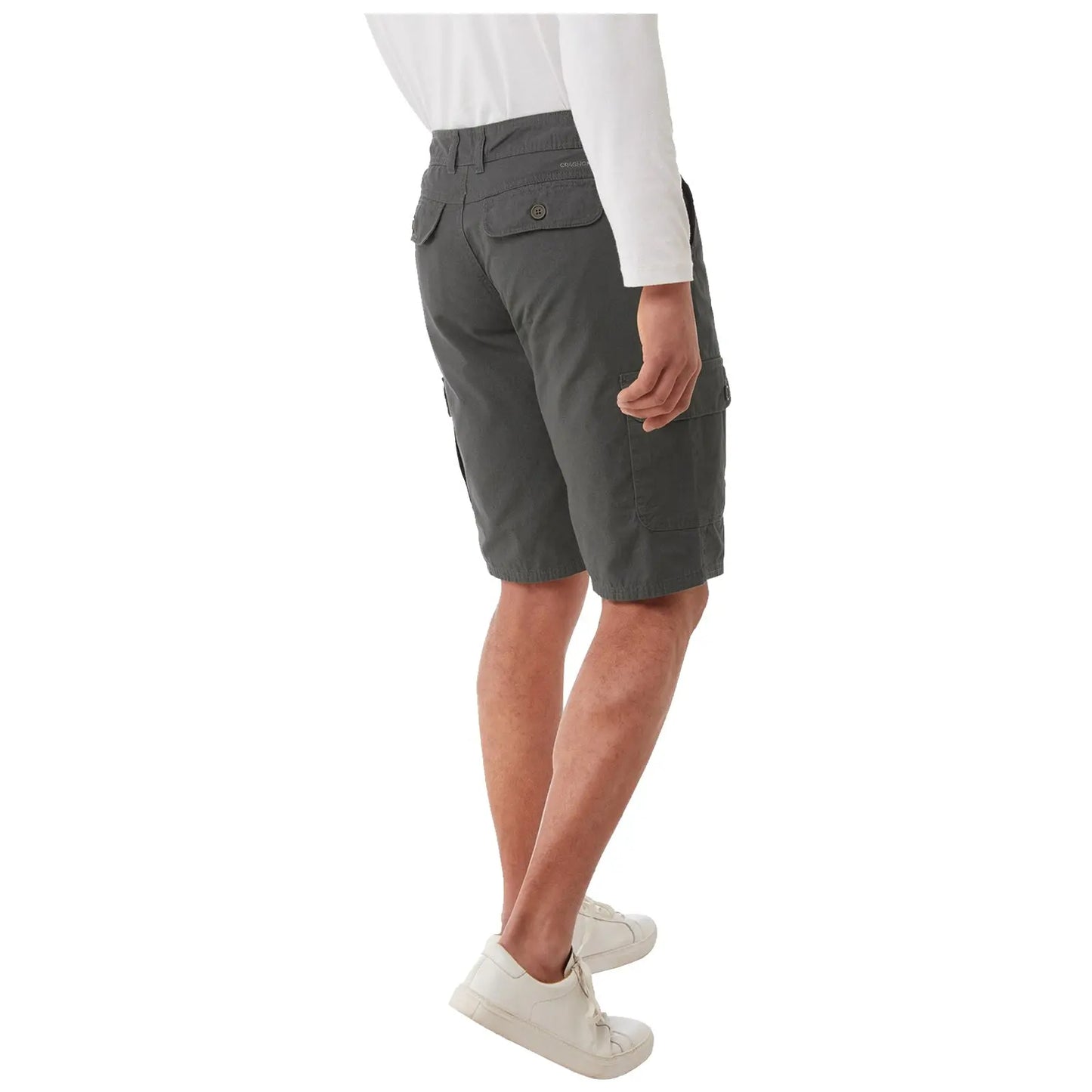 A person is standing with their back towards the viewer wearing gray cargo shorts and white sneakers in a neutral setting. The shorts feature side pockets and a button closure at the waist.