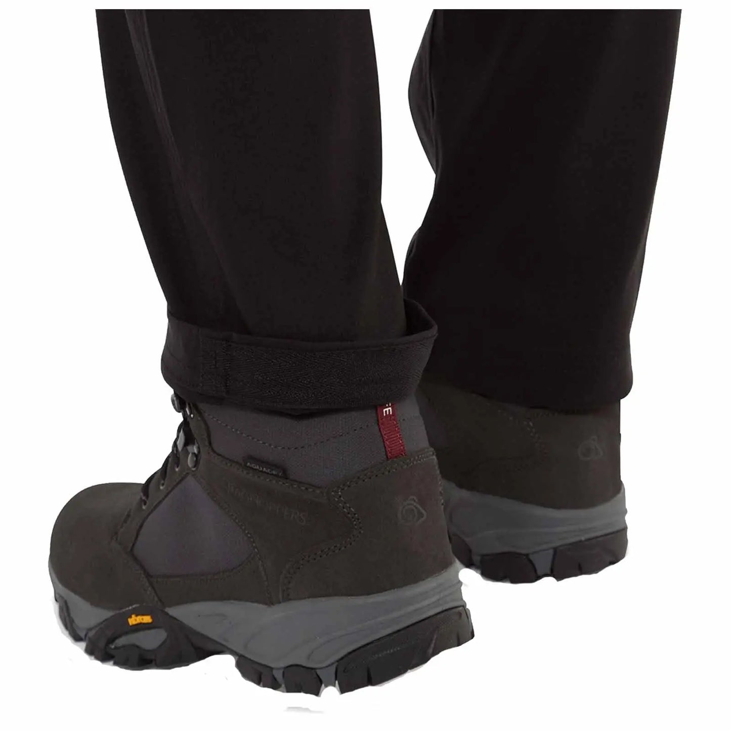 Hiking boots are positioned on a surface with the pant cuffs slightly rolled up revealing the boots designed for outdoor activities in a rugged environment.